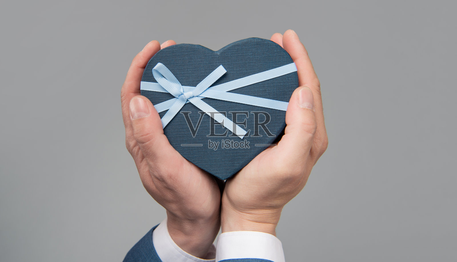 灰色背景上手捧心形礼盒，购买照片摄影图片
