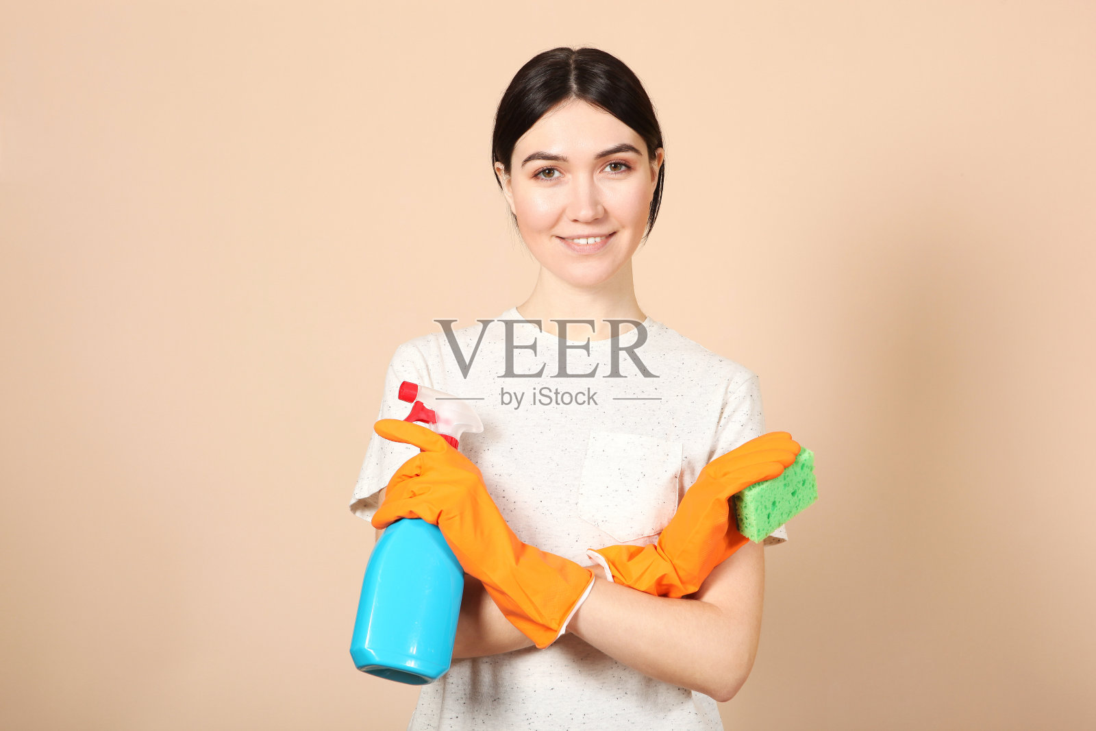 一个年轻的家庭主妇手里拿着彩色背景上的清洁产品。照片摄影图片