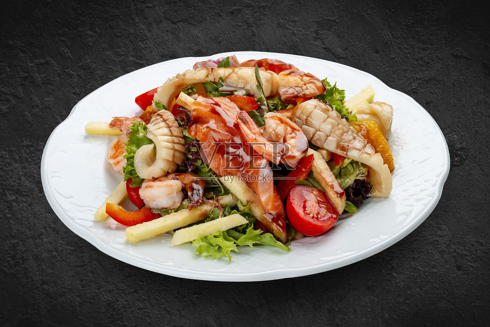 鲜虾、三文鱼、鱿鱼、橙子和甜椒的沙拉。孤立在一个黑色的背景照片摄影图片