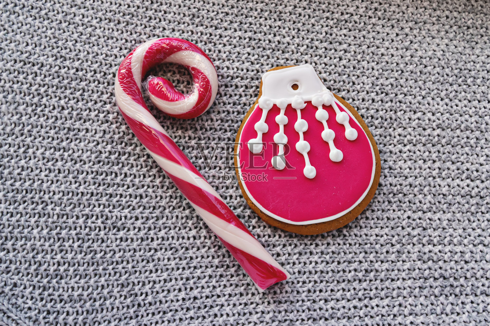 大糖果藤和姜饼饼干与糖霜像圣诞球在针织背景上，平铺。照片摄影图片