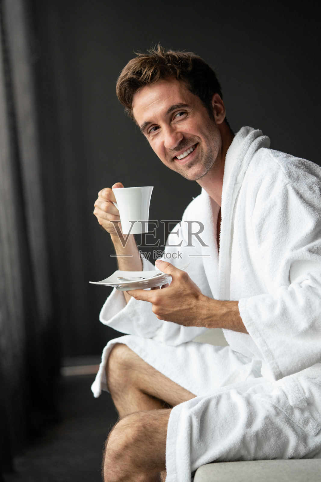 年轻英俊的男人在晨衣喝咖啡照片摄影图片