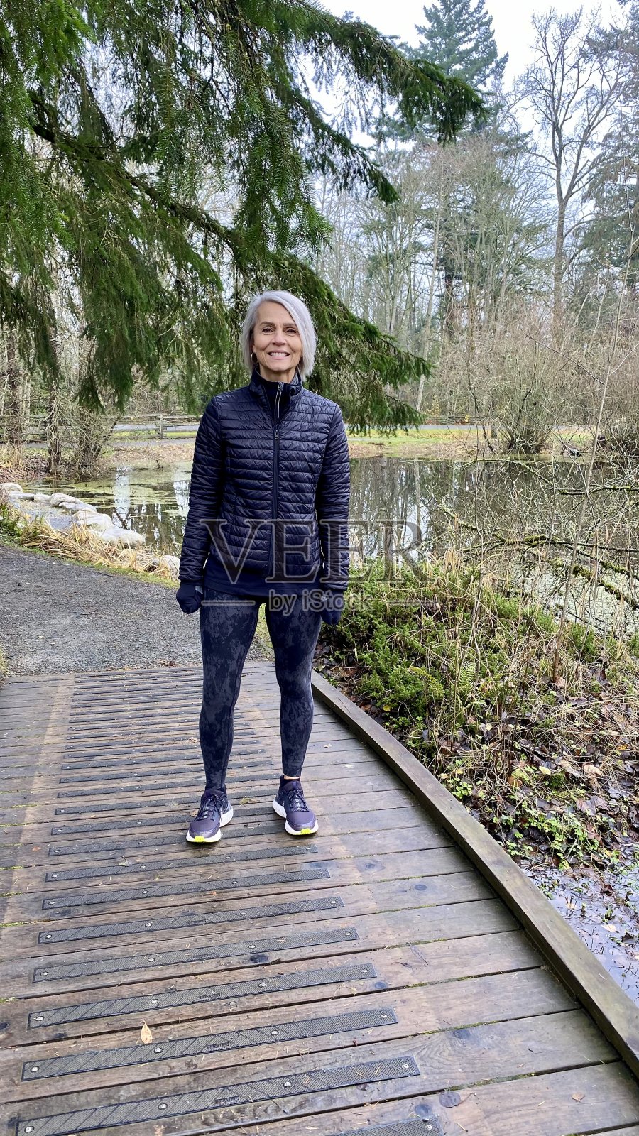 老妇人站在步行桥上照片摄影图片