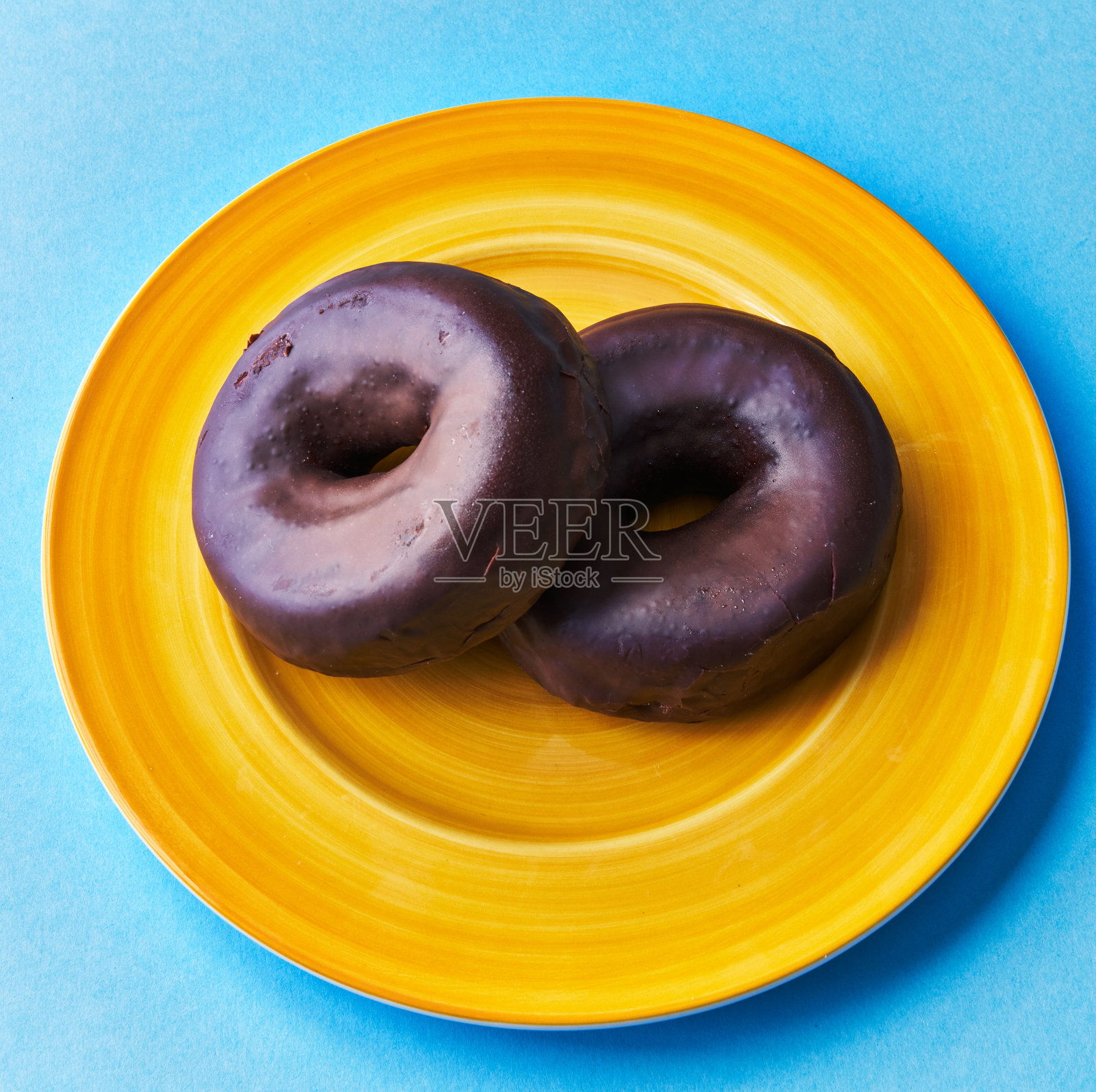 两盘巧克力甜甜圈，蓝色背景照片摄影图片