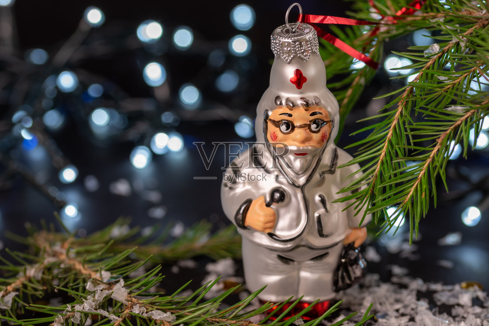 玻璃玩具医生，云杉树枝和圣诞花环。照片摄影图片