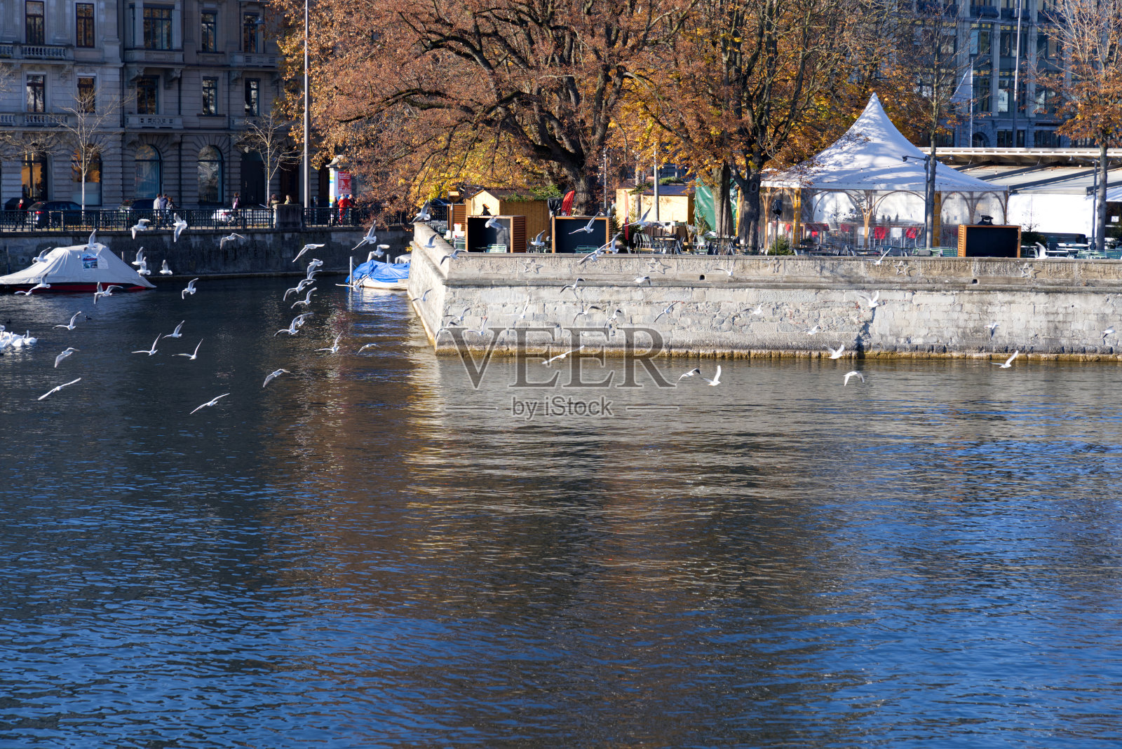 在一个阳光明媚的秋日，在Zürich老城的利马特河和有石墙的露天餐厅。照片摄影图片