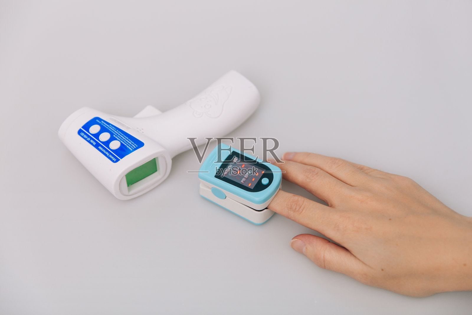 脉搏血氧计和温度计枪在白色背景上。红外等温枪检查体温是否有病毒症状。测量氧饱和度，脉搏率和氧含量照片摄影图片