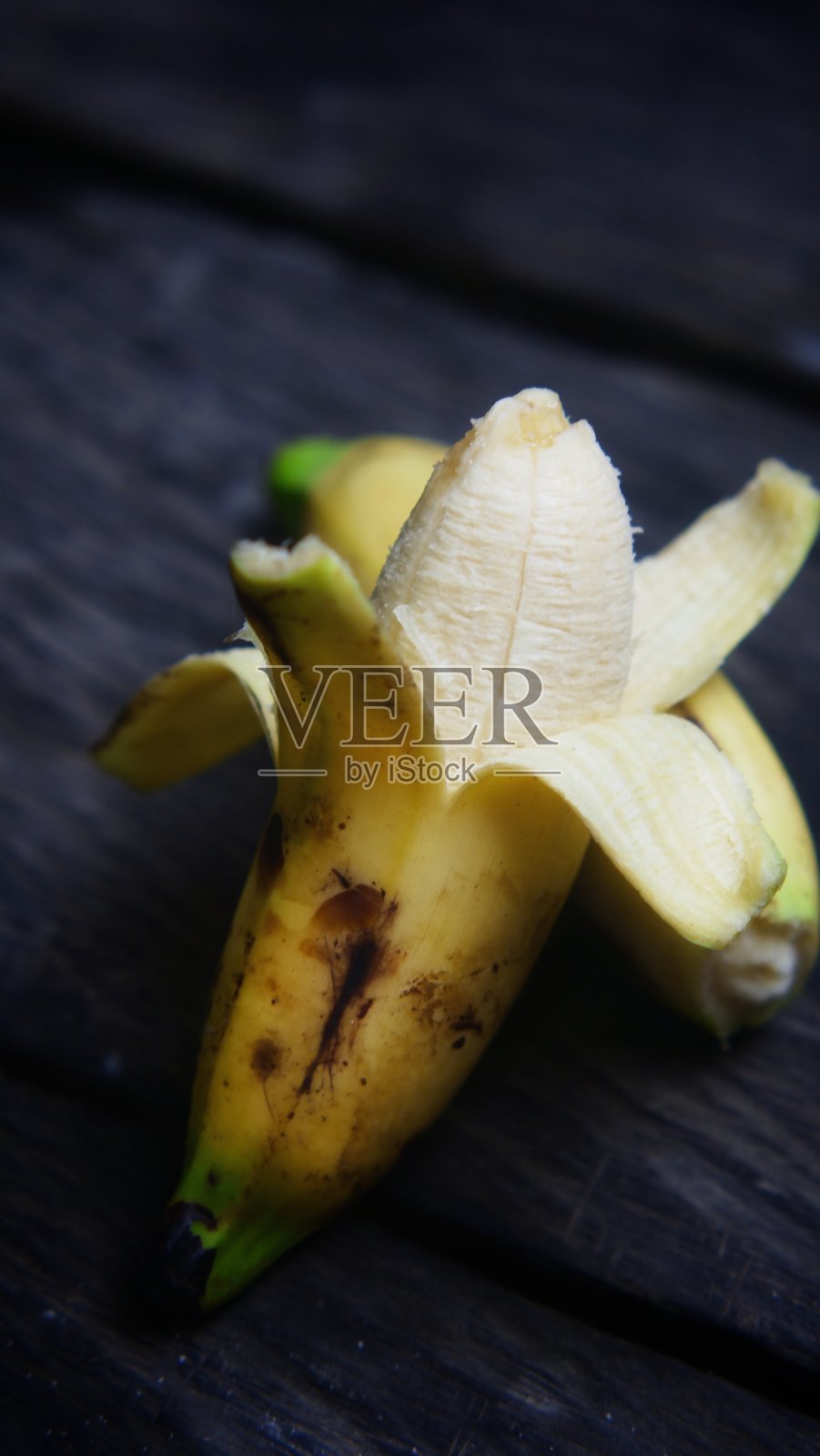 成熟的香蕉，已去部分皮，可以放在木桌上吃照片摄影图片