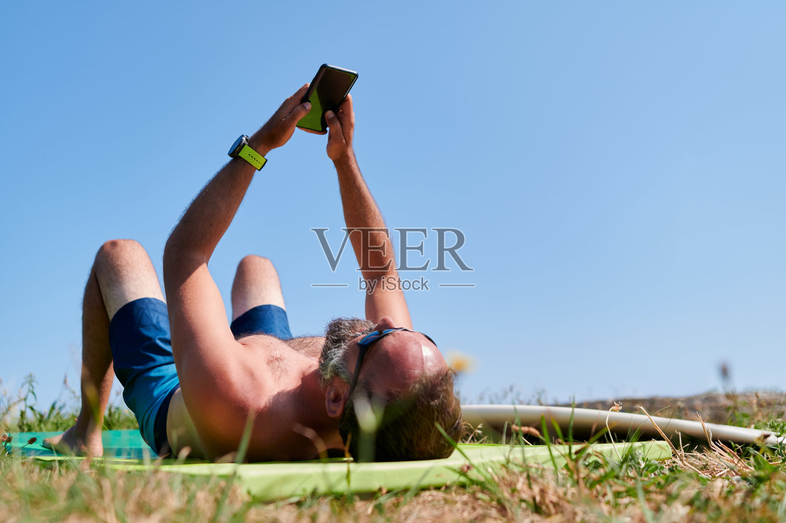 成熟的冲浪者使用智能手机在海滩上照片摄影图片