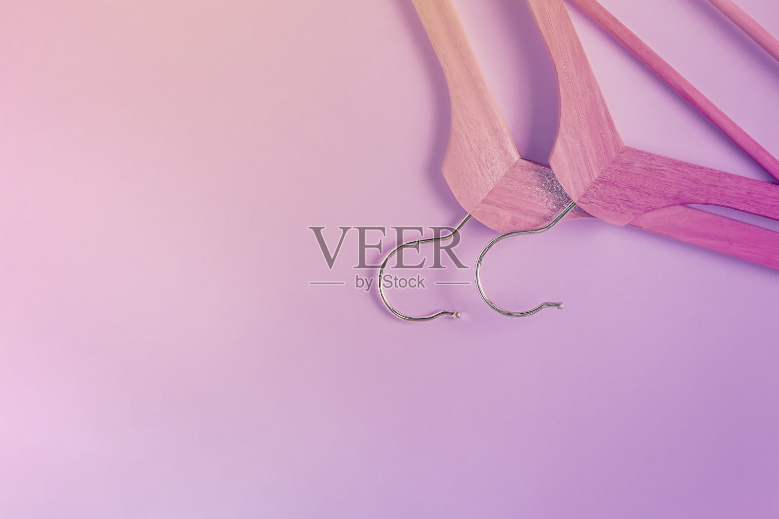 紫色背景上的两个木制衣架倒立着。平面布局，复制空间，水平背景。衣架，购物概念，销售照片摄影图片