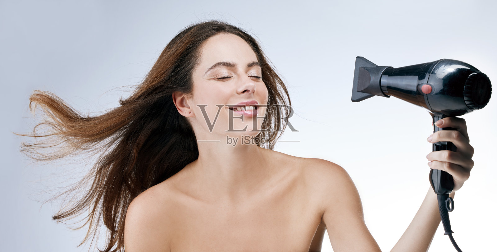 一个女人站在白色背景下吹头发照片摄影图片