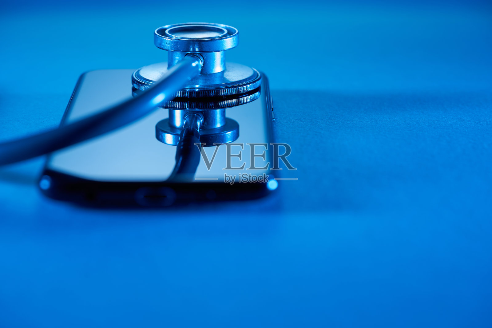 带医疗app的手机放在木桌上，配有听诊器照片摄影图片