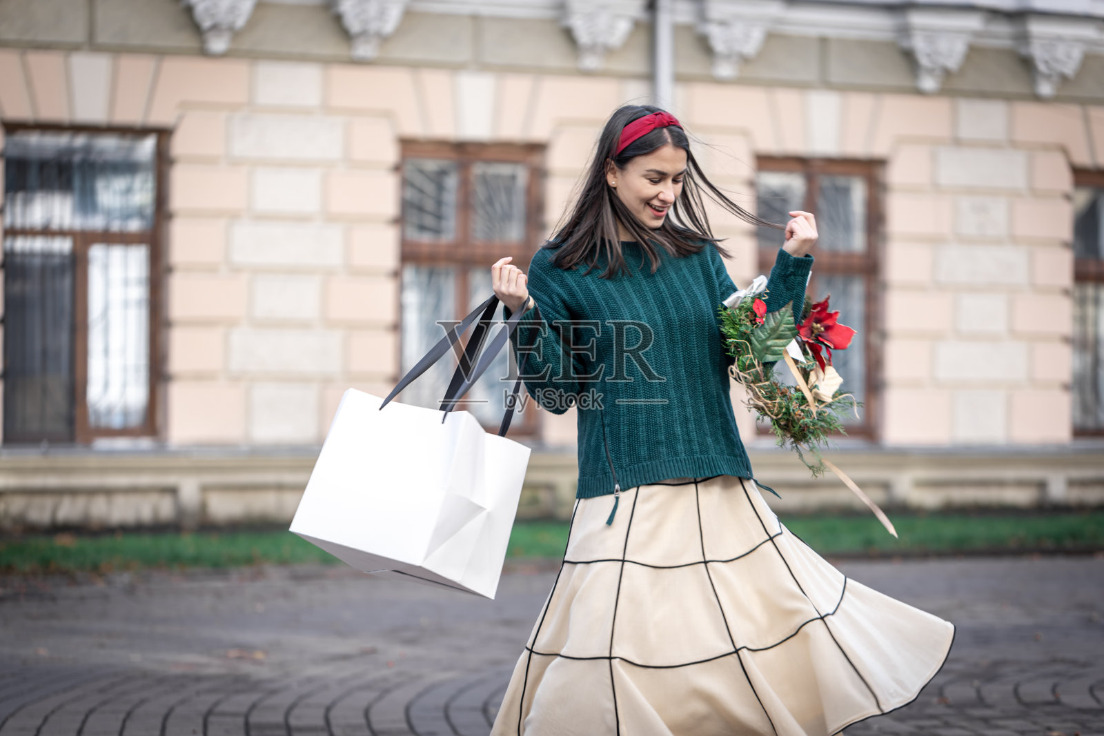 年轻女子拿着圣诞礼物在外面购物。照片摄影图片