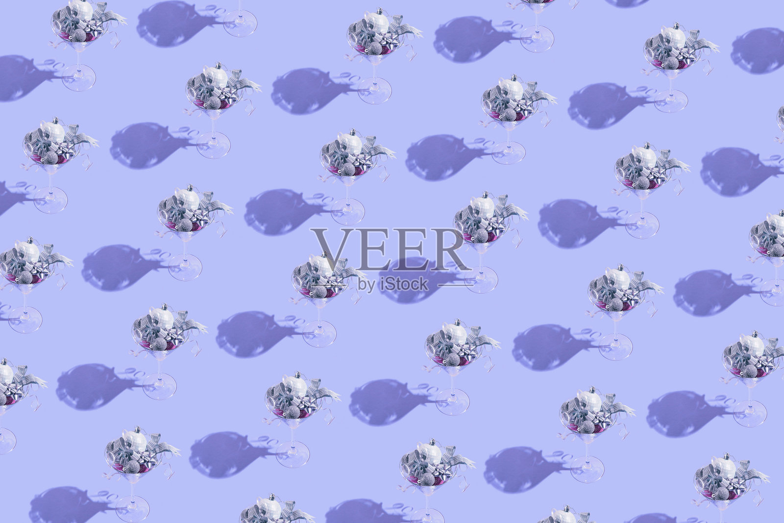 由马提尼玻璃制成的创意图案，在淡紫色的背景上装饰银饰和蝴蝶结。派对和节日的概念。圣诞节庆祝活动的主题。最小的风格照片摄影图片