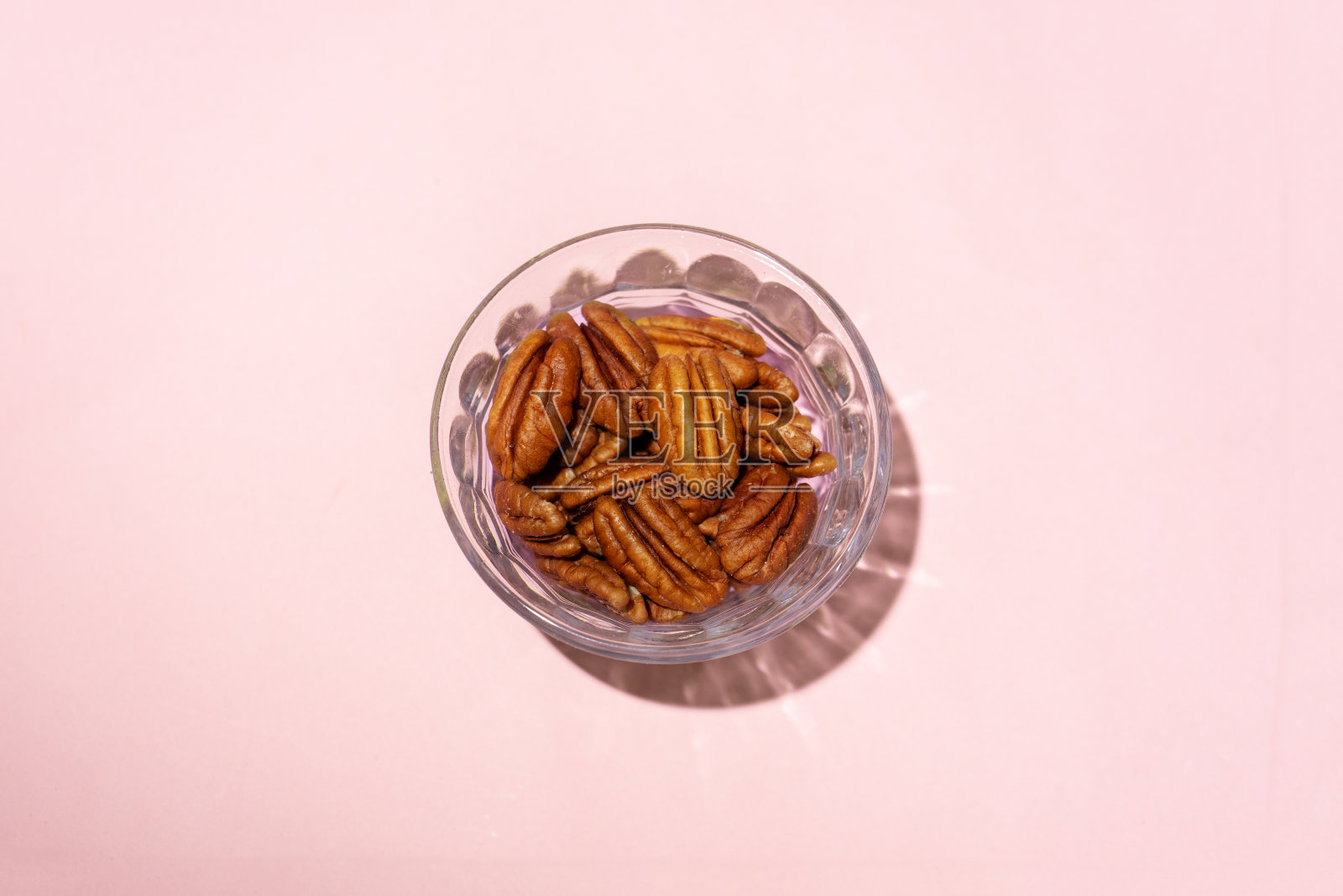核桃在粉红色背景的玻璃碗里照片摄影图片