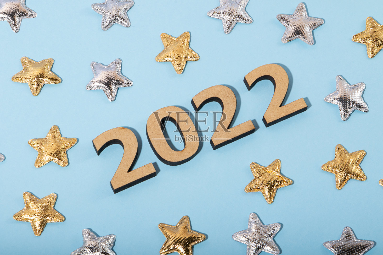 在蓝色背景上的木号2022的俯视图。周围有金色和银色的星星。节日的概念。照片摄影图片