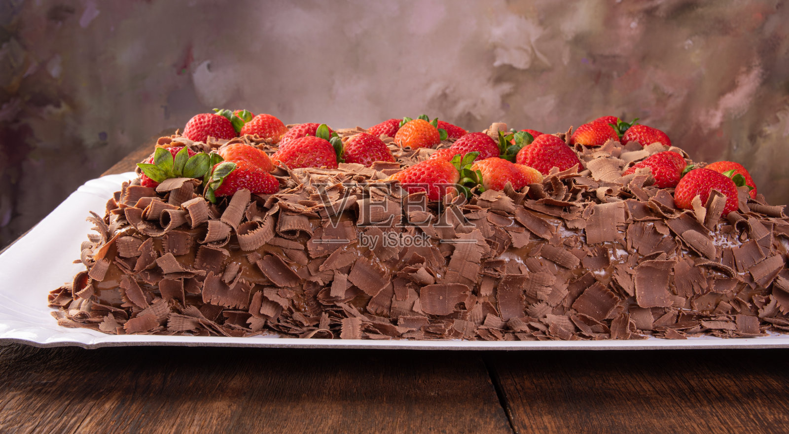 巧克力蛋糕，一个美丽的巧克力蛋糕草莓上的白色形状的乡村木材，抽象的背景，选择性的焦点。照片摄影图片