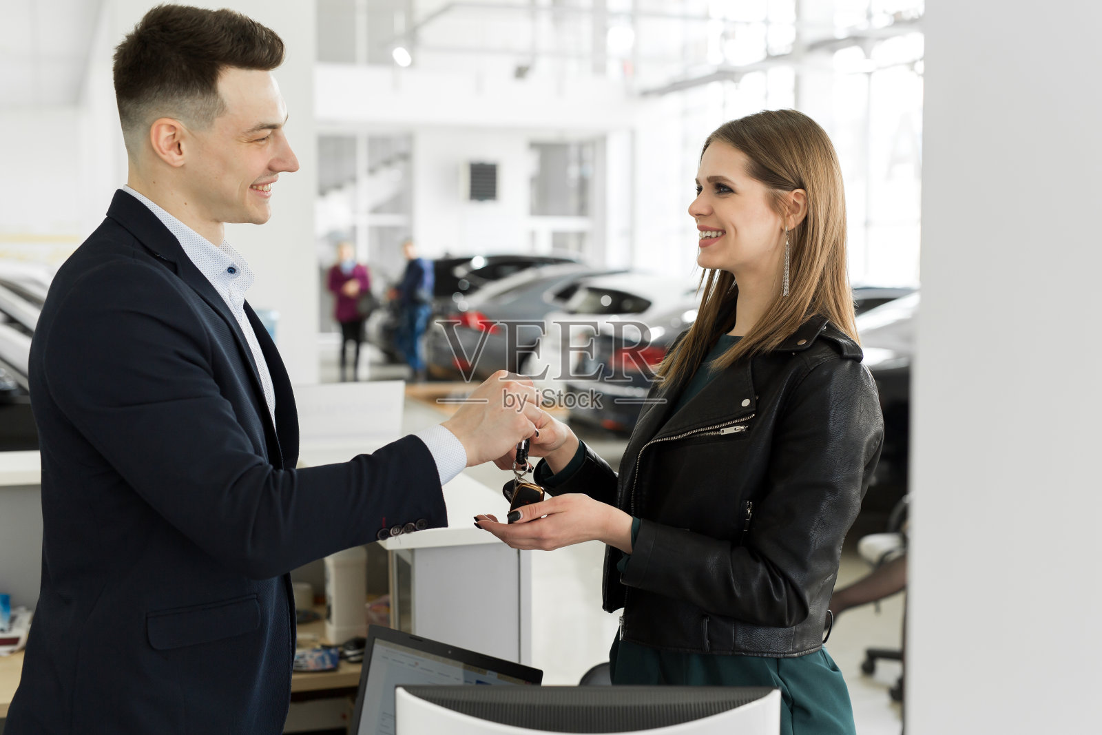 汽车租赁和保险概念，年轻的销售人员在与客户签订协议后，接受资金并将汽车钥匙交给客户。照片摄影图片