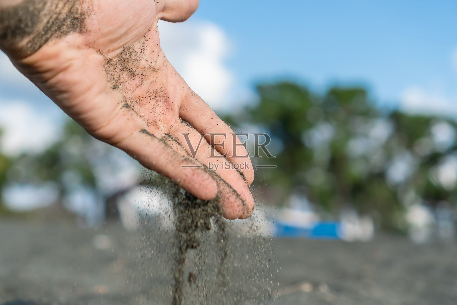 灰色的沙子从一个男人的手指间倾泻而出的特写，复制空间照片摄影图片