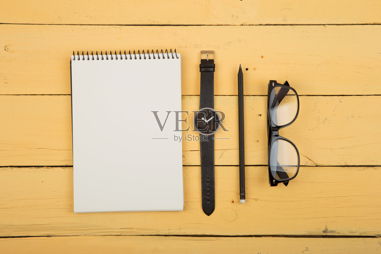黄色木桌上的笔记本、眼镜、手表和铅笔，顶视图，文字空间照片摄影图片