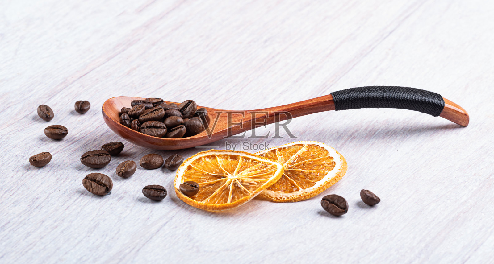 木勺里的咖啡豆和浅木质背景上的干橙子照片摄影图片