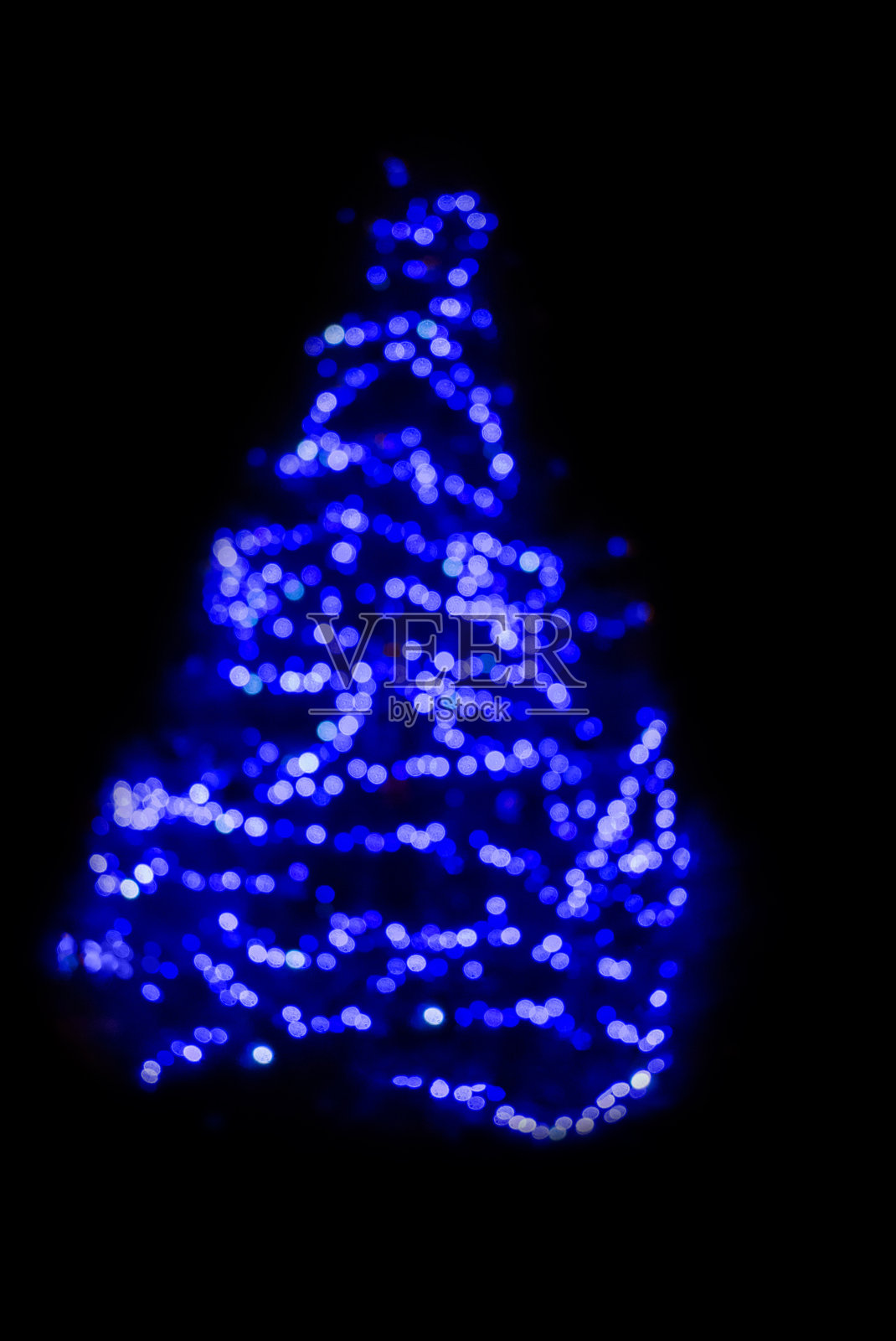 黑色背景下的圣诞树上有蓝色的灯。使用散焦模拟对整个镜头进行散焦照片摄影图片