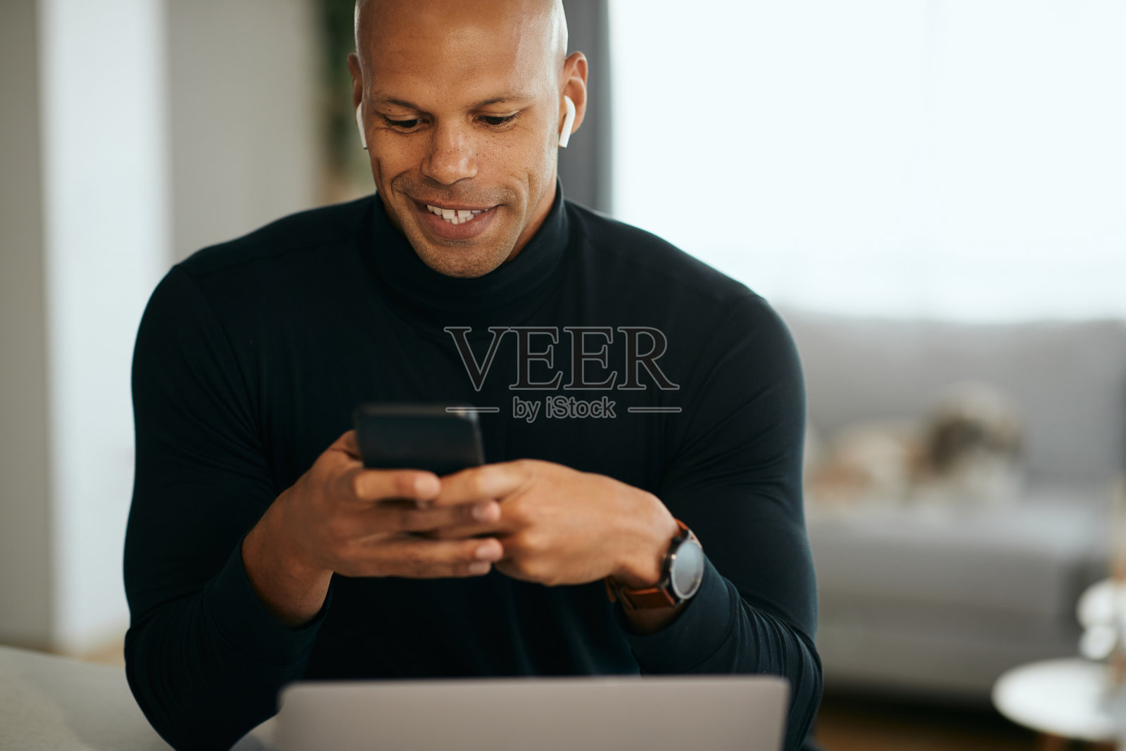 快乐的黑人经理在家里工作时用手机发短信。照片摄影图片