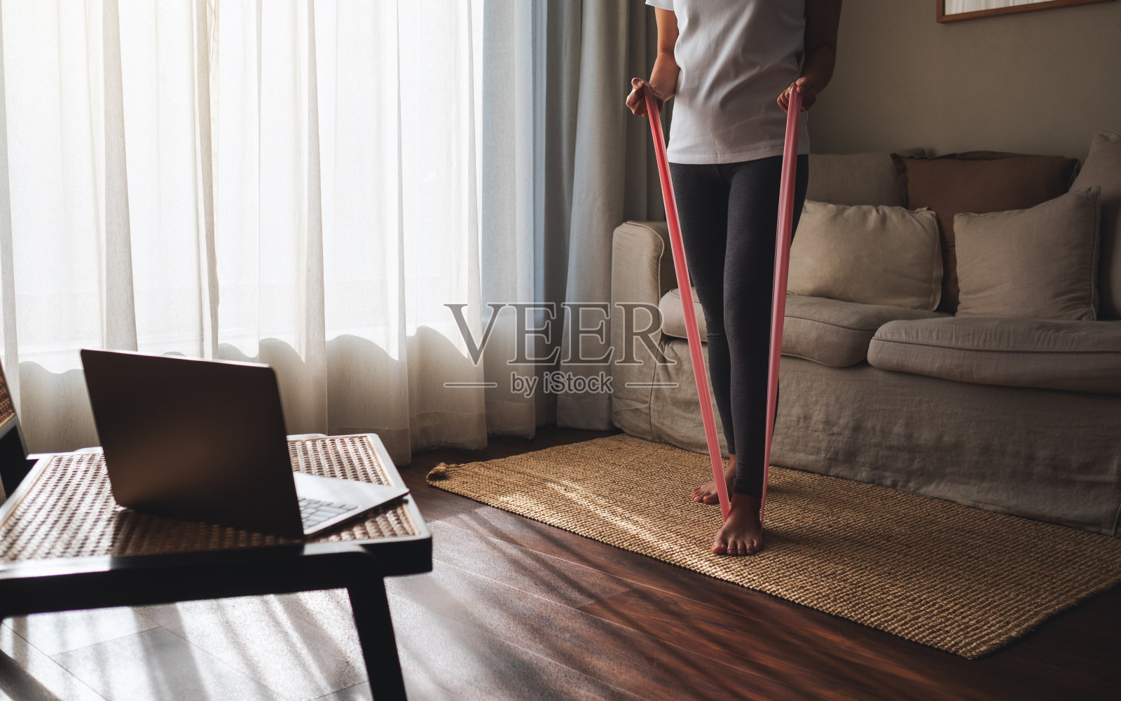 一名妇女在家用橡胶阻力带在线锻炼照片摄影图片
