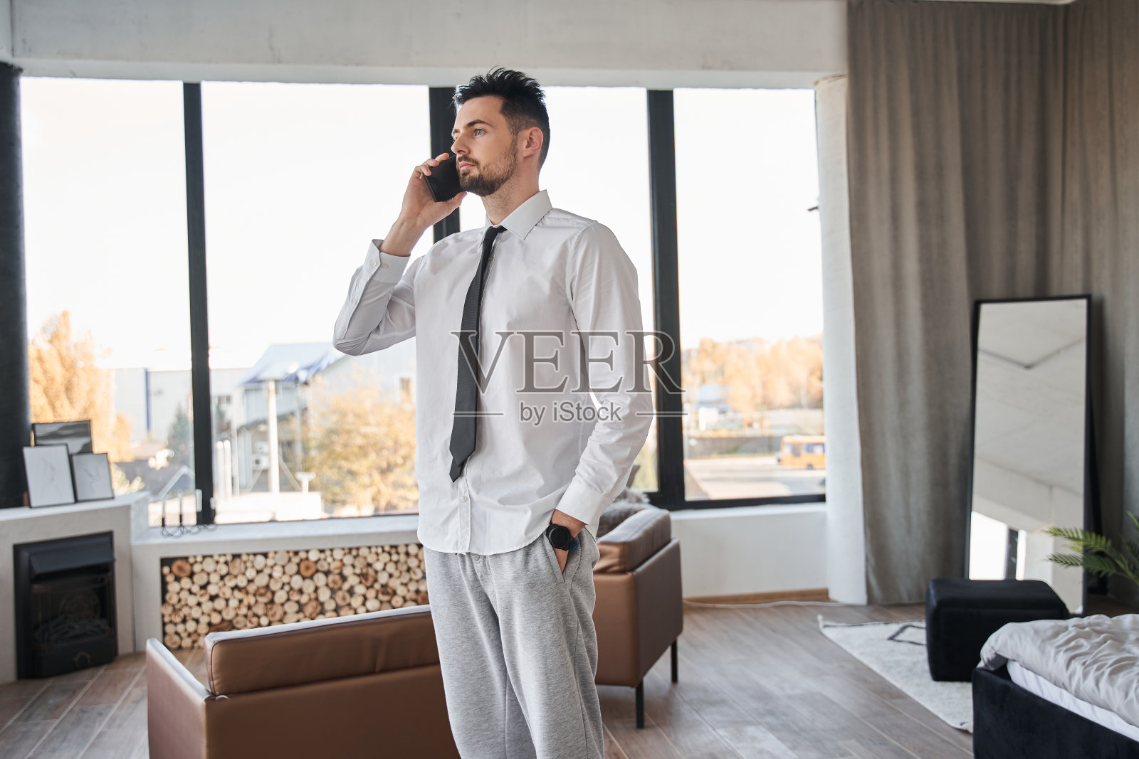 一个商人站在他的公寓里用手机聊天照片摄影图片