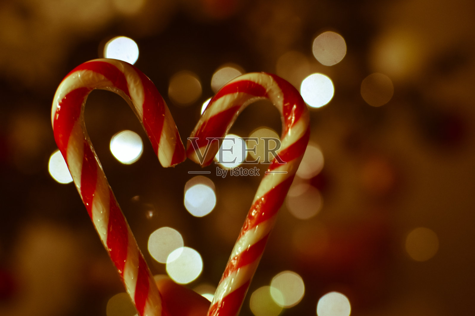 手拿着心形的圣诞棒棒糖和散景灯照片摄影图片