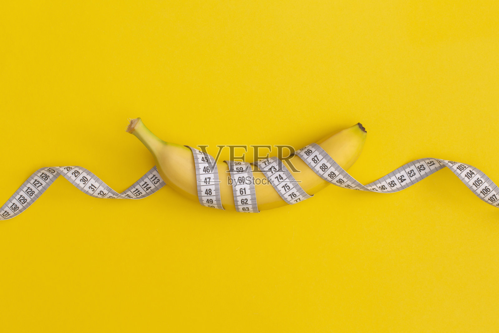 卷尺和香蕉在黄色背景上。减肥的概念照片摄影图片