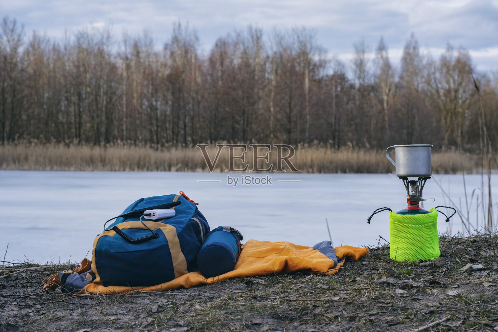 旅行时给智能手机充电。便携式充电器在游客的煤气炉和森林的背景下为手机充电。照片摄影图片