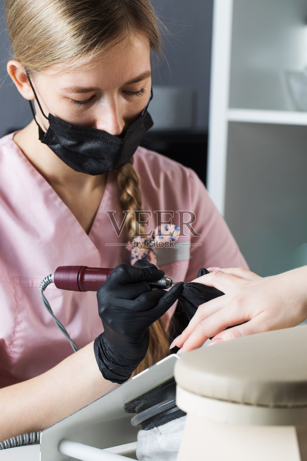 硬件修指甲。修甲过程中，用切割机去除角质层。用电子锉刀加工指甲。照片摄影图片