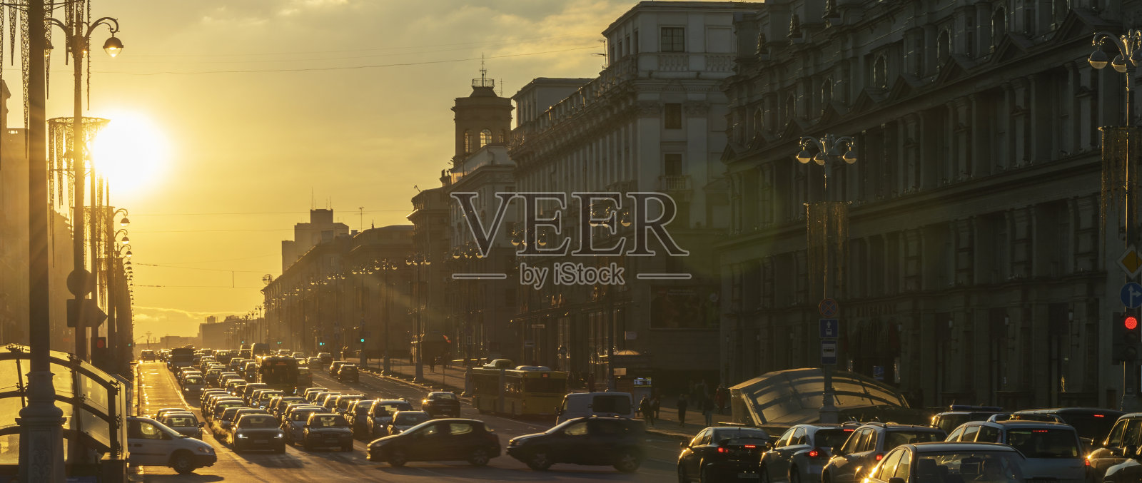 城市中建筑物之间的日落全景。在路的尽头，太阳在地平线上落下。照片摄影图片