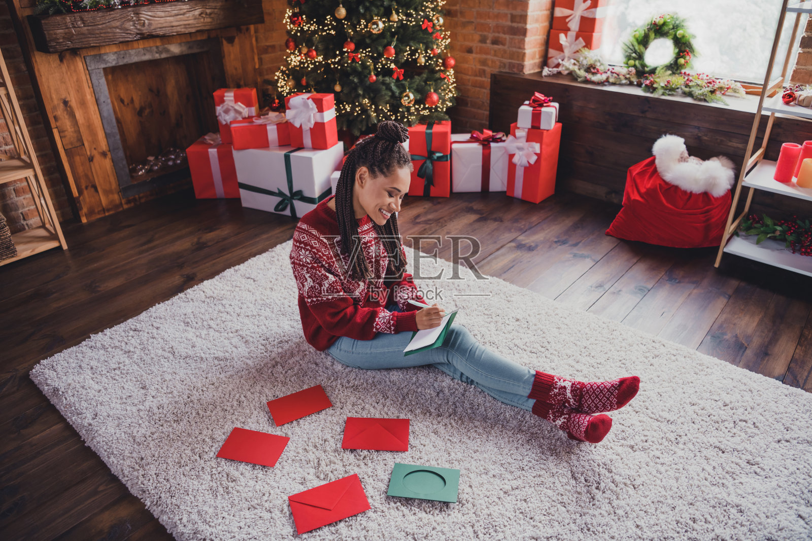 照片中的非洲妇女看着相机喜气洋洋的微笑享受圣诞夜穿套衫在室内装饰的家照片摄影图片