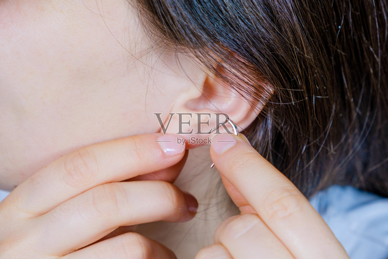 一个女人在她的耳朵上戴了一个金耳环。照片摄影图片