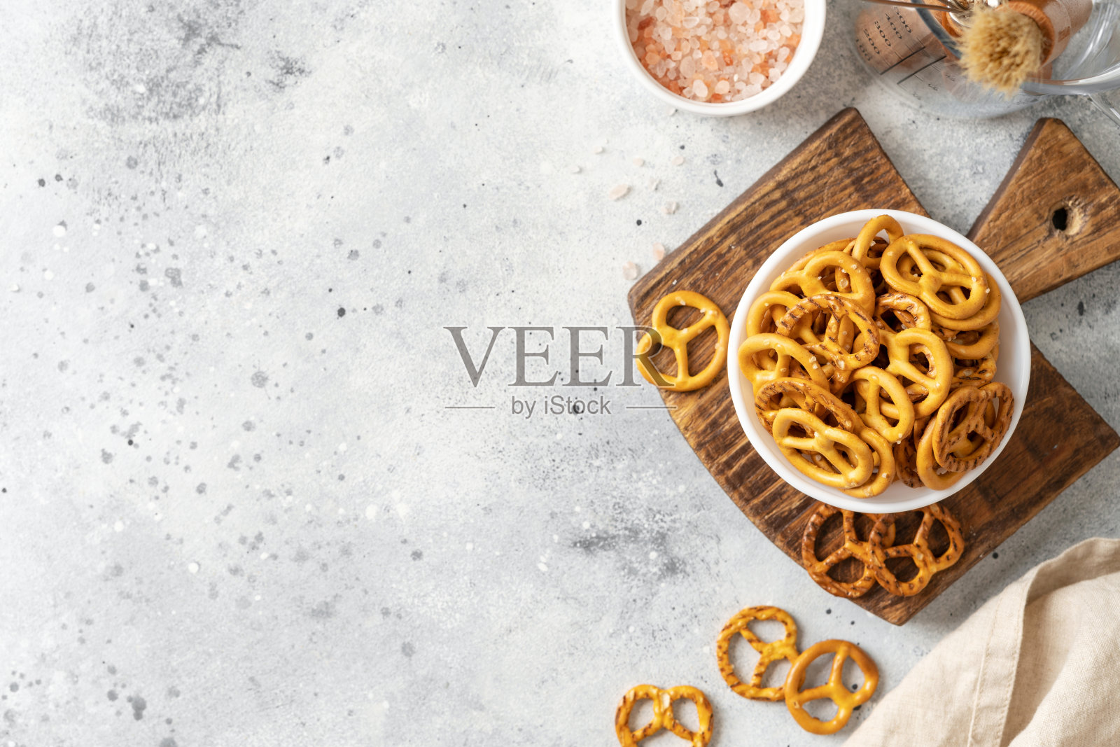 在明亮的厨房餐桌上，白色的碗里放着迷你椒盐脆饼照片摄影图片