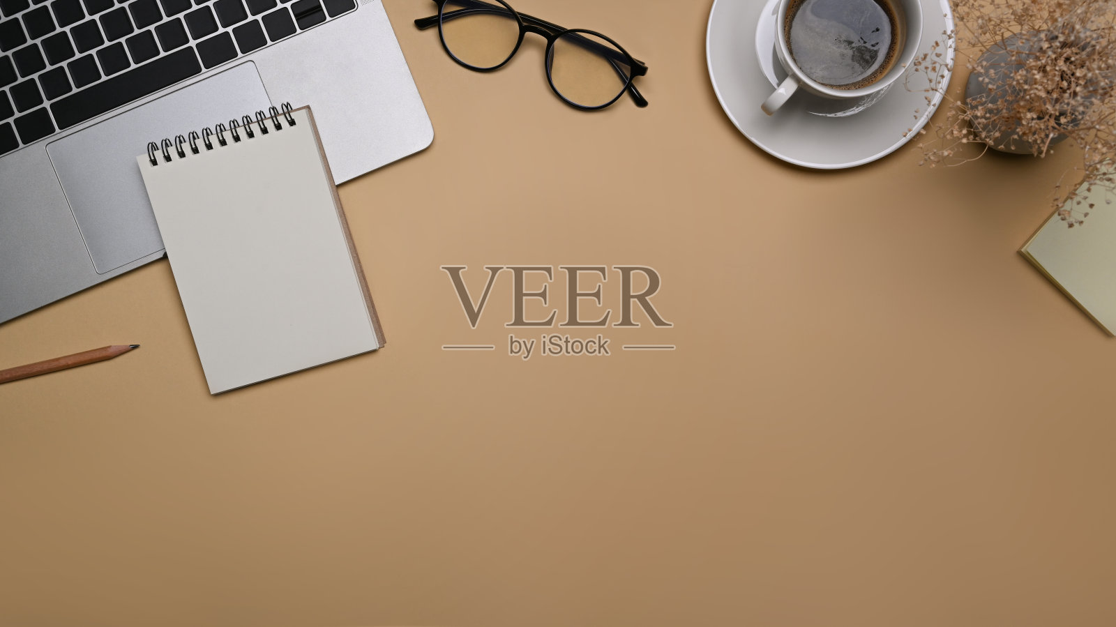 舒适的工作空间与笔记本电脑，眼镜和笔记本电脑在米色的背景。照片摄影图片