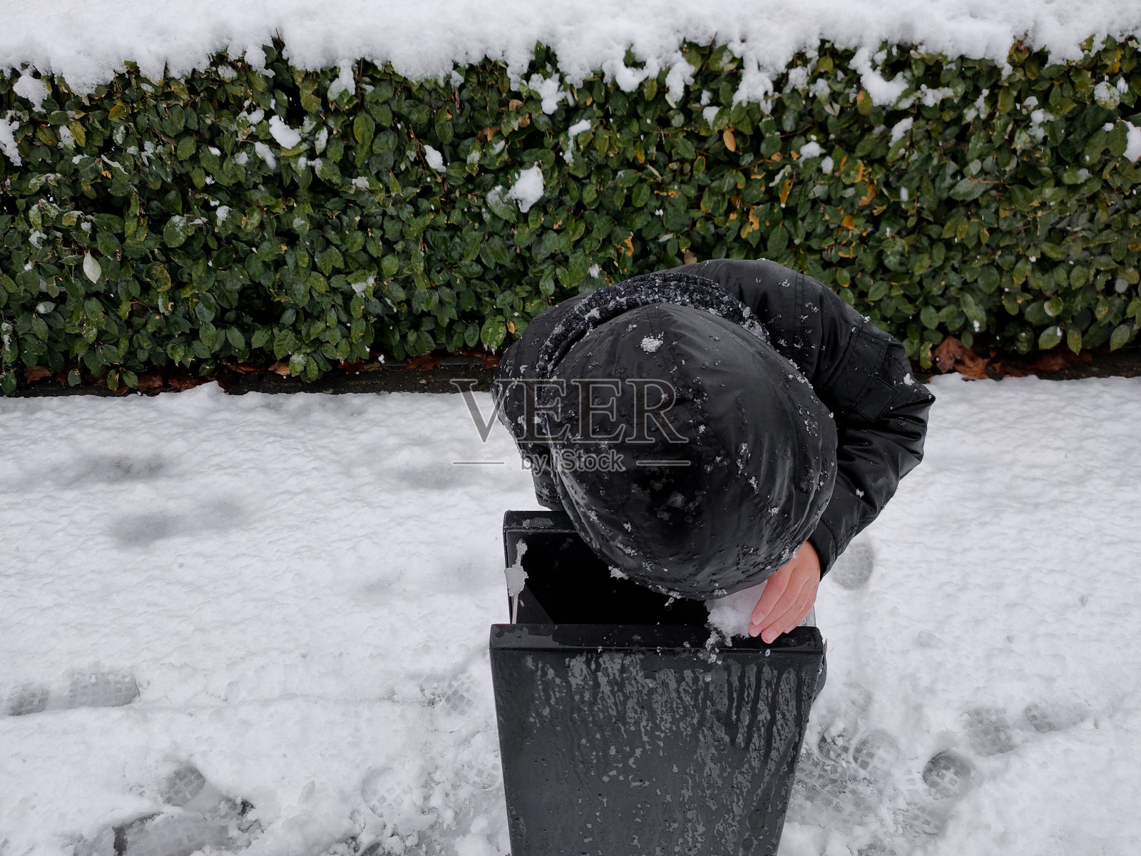 在寒冷的冬天，男孩喝冰水照片摄影图片