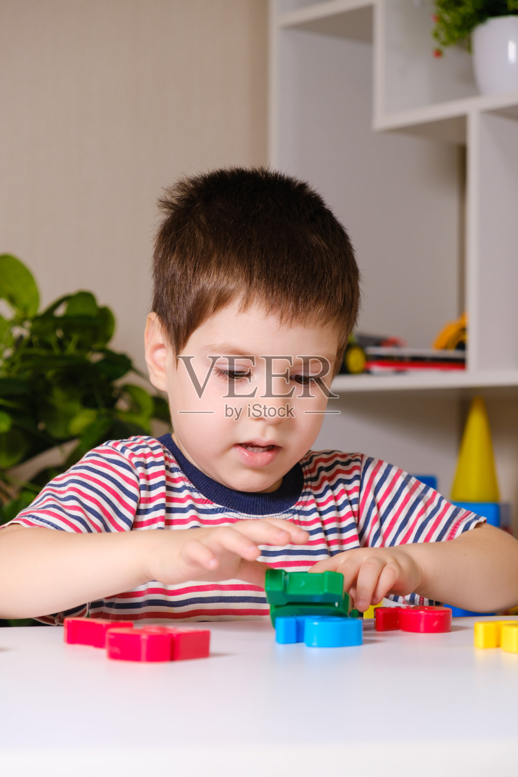 一个四岁的男孩玩彩色数字，建一座塔照片摄影图片