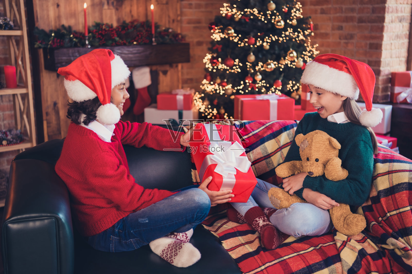 肖像的两个有吸引力的开朗的兄弟姐妹坐在沙发上给予处理礼品盒祝贺在阁楼的家在室内照片摄影图片
