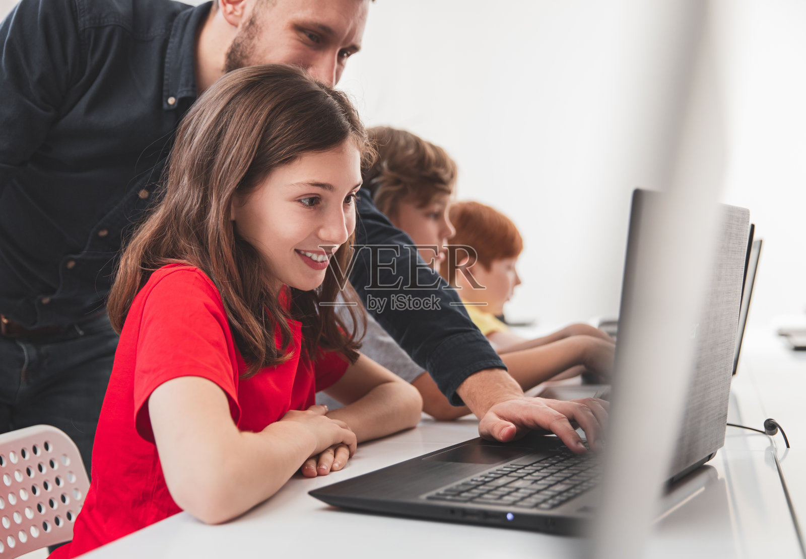 快乐的女学生与老师工作在笔记本电脑在课上照片摄影图片