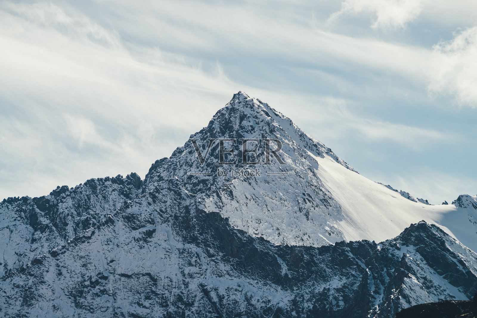 伟大的观点，高的雪山墙与顶峰下的天空卷云。高山景观，在阳光下有巨大的雪山和尖顶。阳光下的白雪尖峰。照片摄影图片