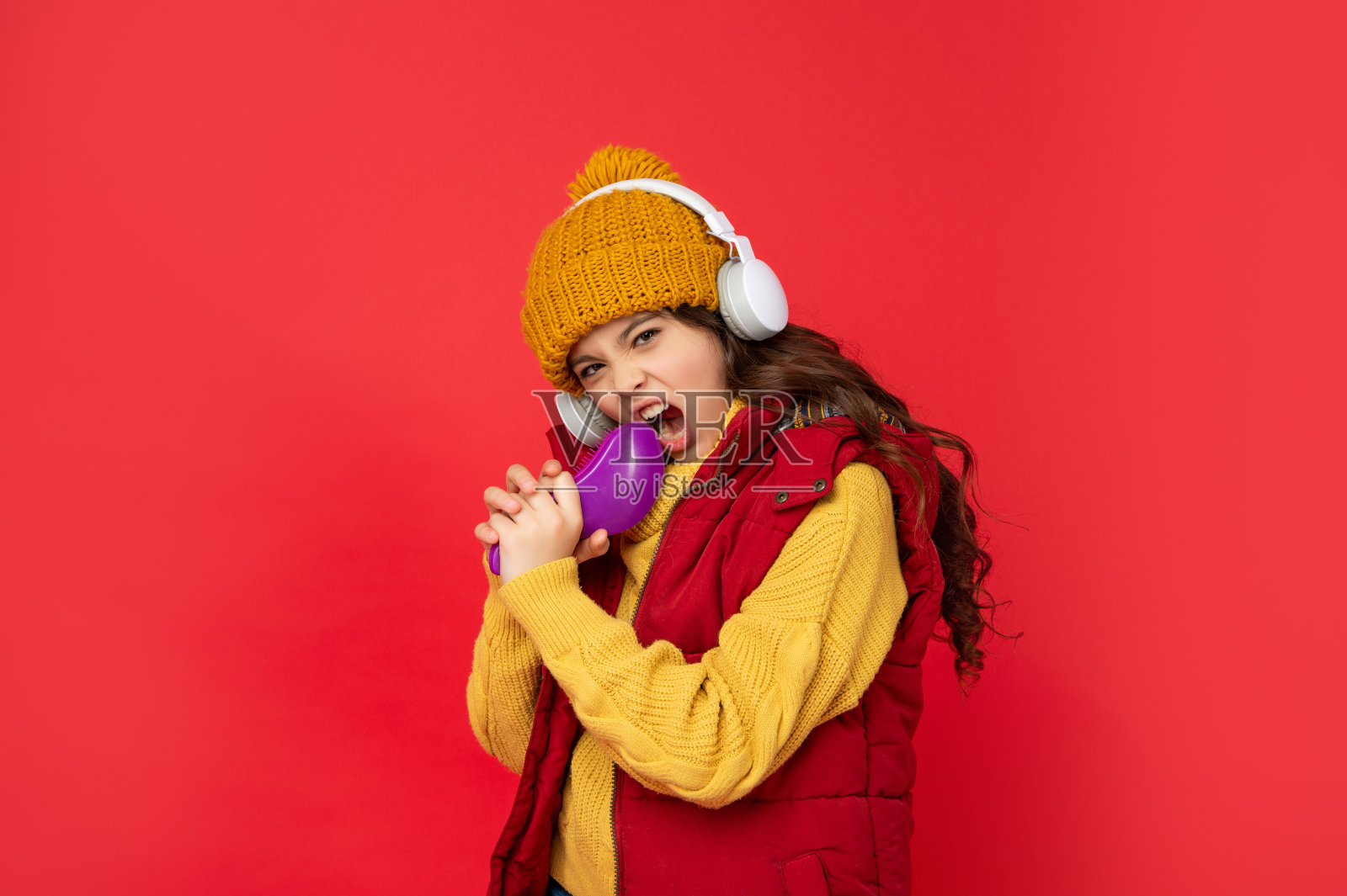 欢快的孩子戴着帽子戴着耳机听音乐，梳着梳子唱歌照片摄影图片