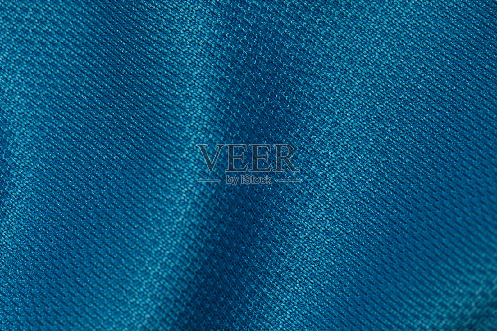 蓝色织物表面的波浪。以密集编织的光滑材料的皱褶纹理为图案背景照片摄影图片