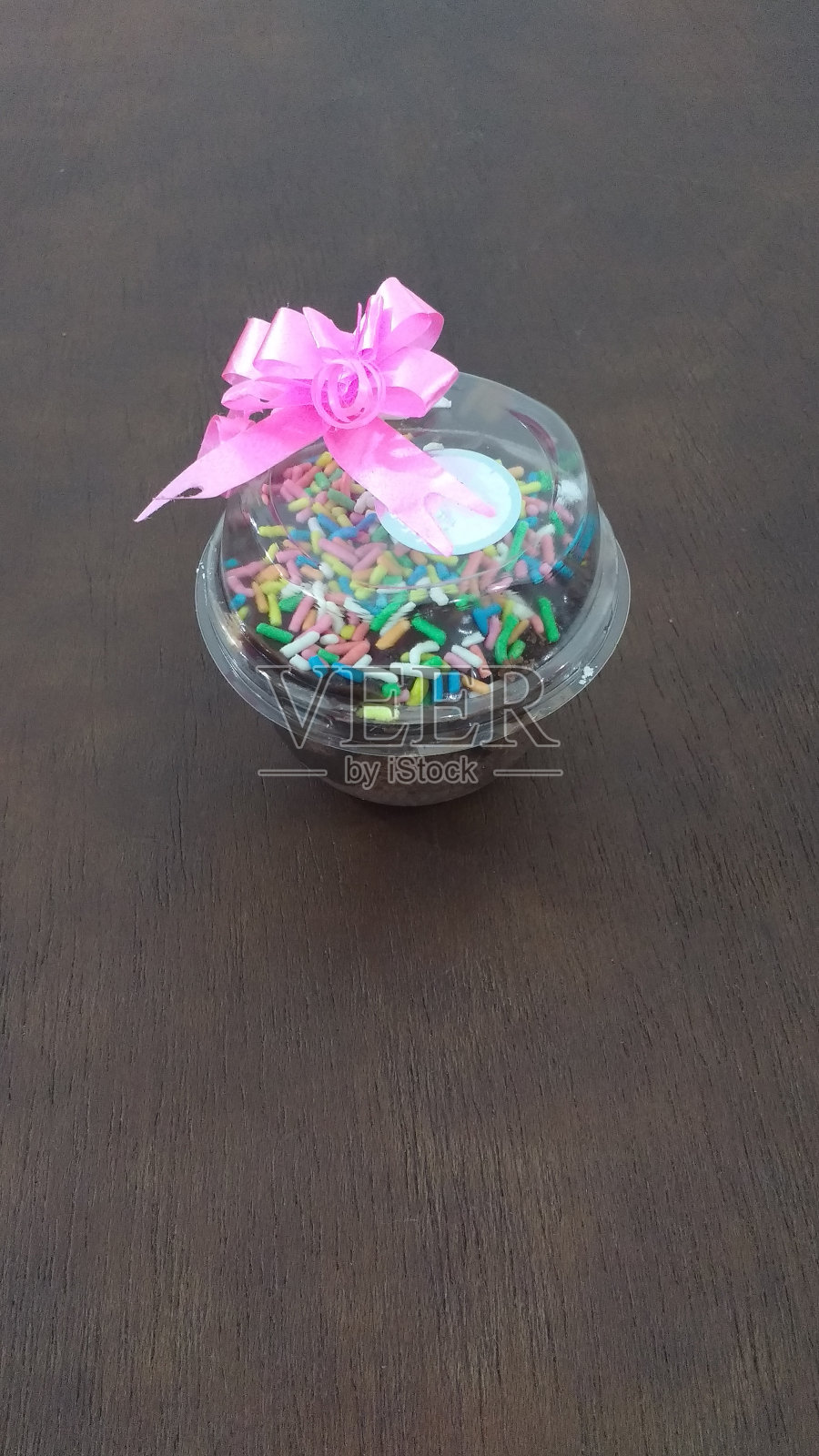 巧克力味的锅蛋糕，有彩色的点缀，盖子上有粉红色的蝴蝶结。照片摄影图片