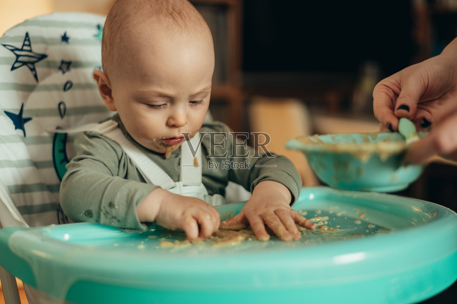 婴儿坐在儿童餐椅上吃东西，脸上沾着食物照片摄影图片