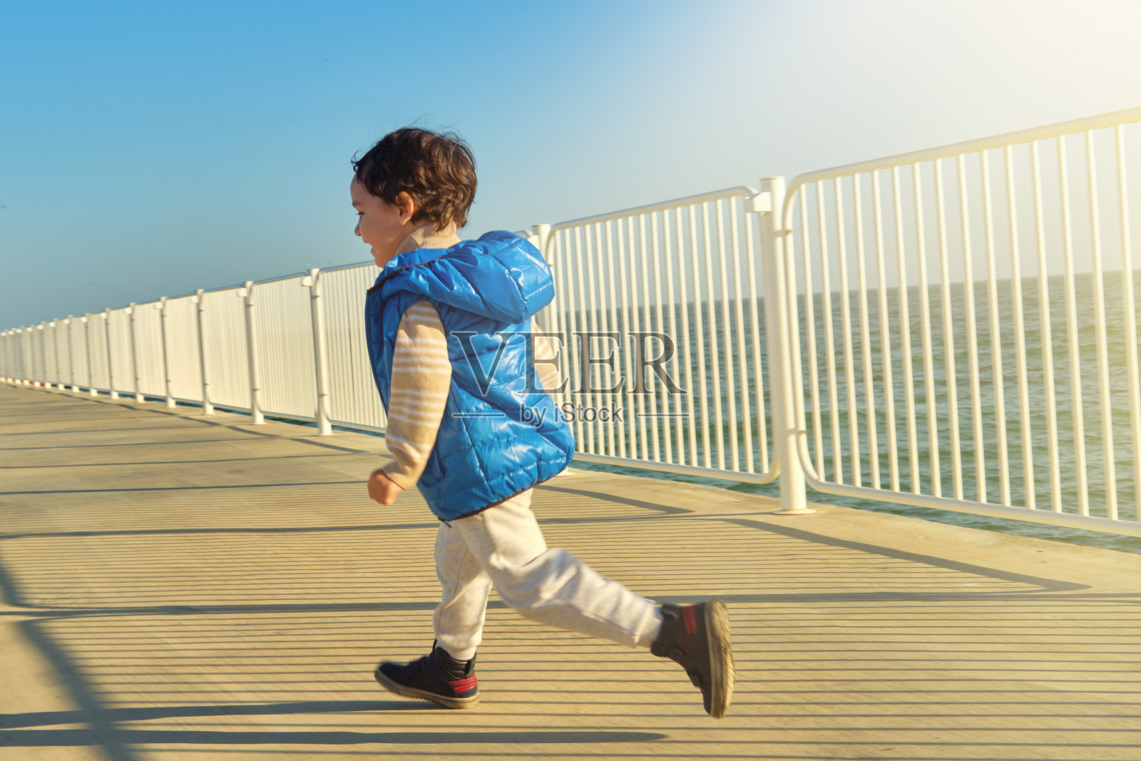 快乐的小男孩沿着堤岸奔跑照片摄影图片