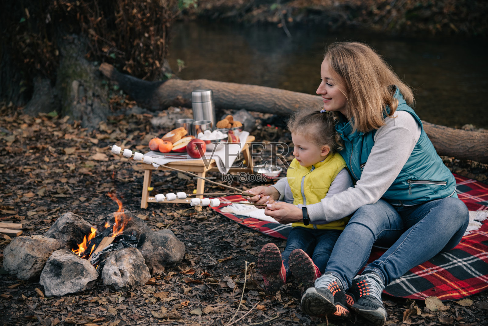 妈妈和女儿在火边烤棉花糖。照片摄影图片