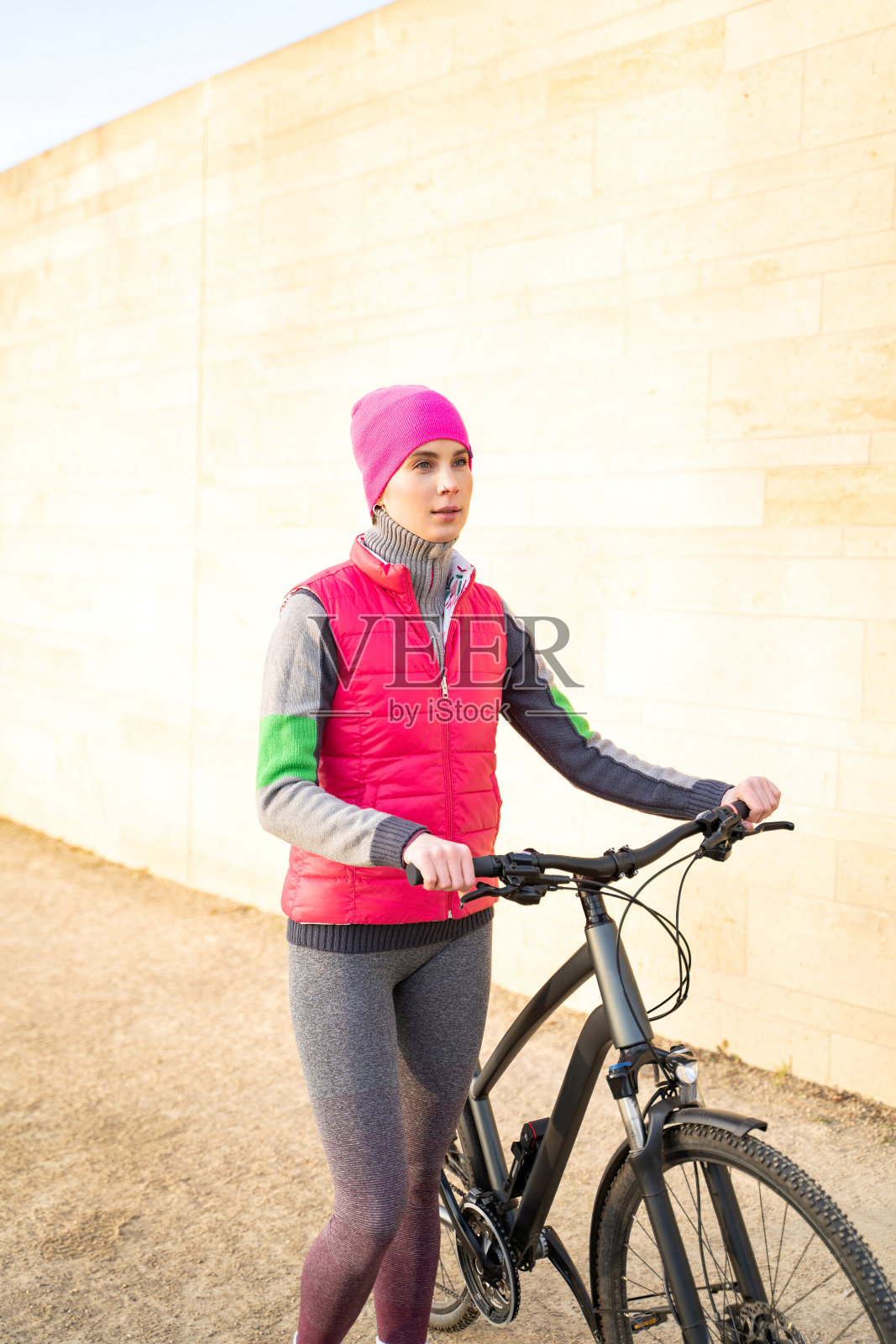 穿着暖和的健身服的年轻女子站在自行车旁边照片摄影图片