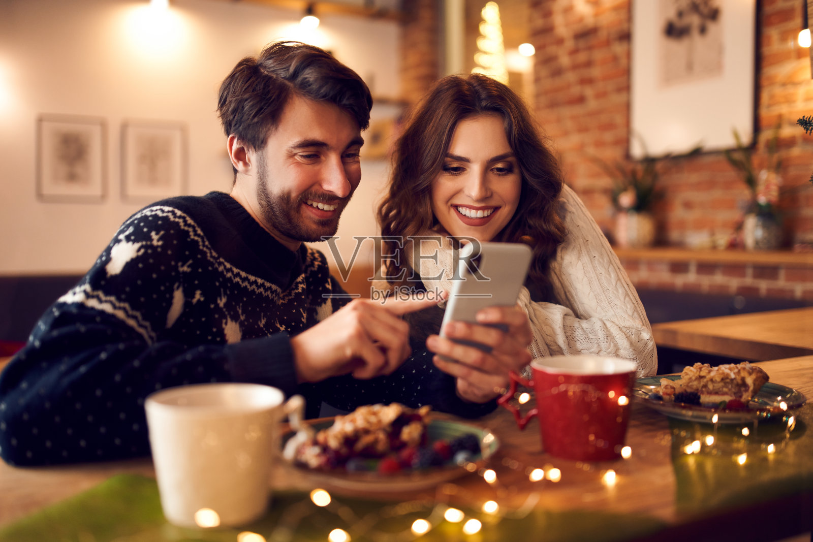 圣诞节期间，情侣们在咖啡馆里使用智能手机照片摄影图片
